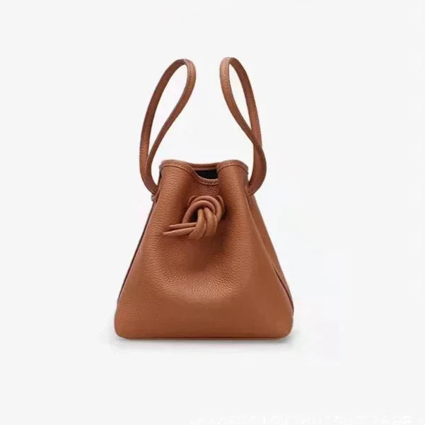 A stylish brown leather bag with a unique knot design and dual handles - front view.