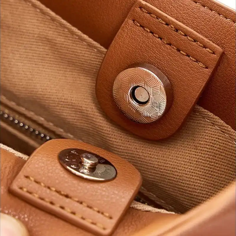 Detail of a magnetic clasp on a brown leather bag, highlighting the high-quality finish and materials.