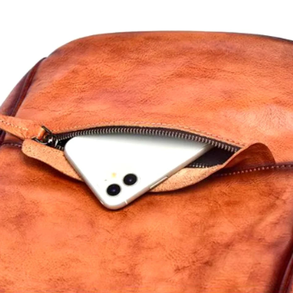 brown leather backpack with a white smartphone partially visible in the zippered pocket. 