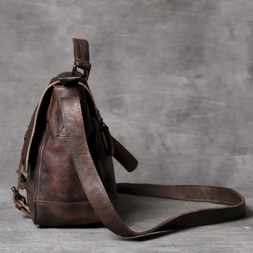 side view of an elegant brown leather bag with a modern design, soft handle and long strap.