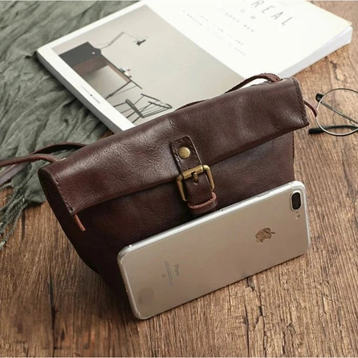  stylish and practical brown leather bag, with a cell phone for size reference, front view.