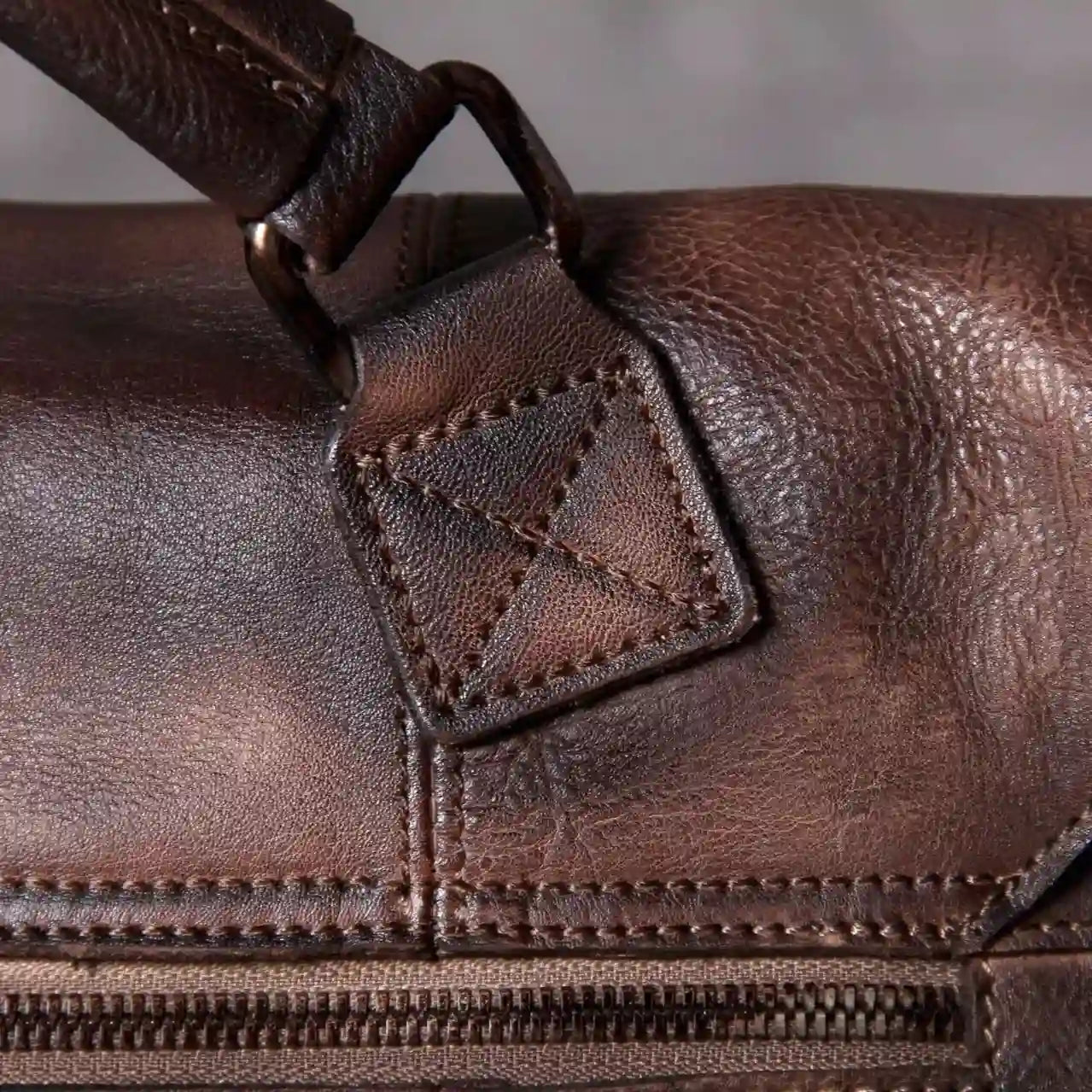 Detail of a brown leather bag, highlighting the texture, stitching and accessories.