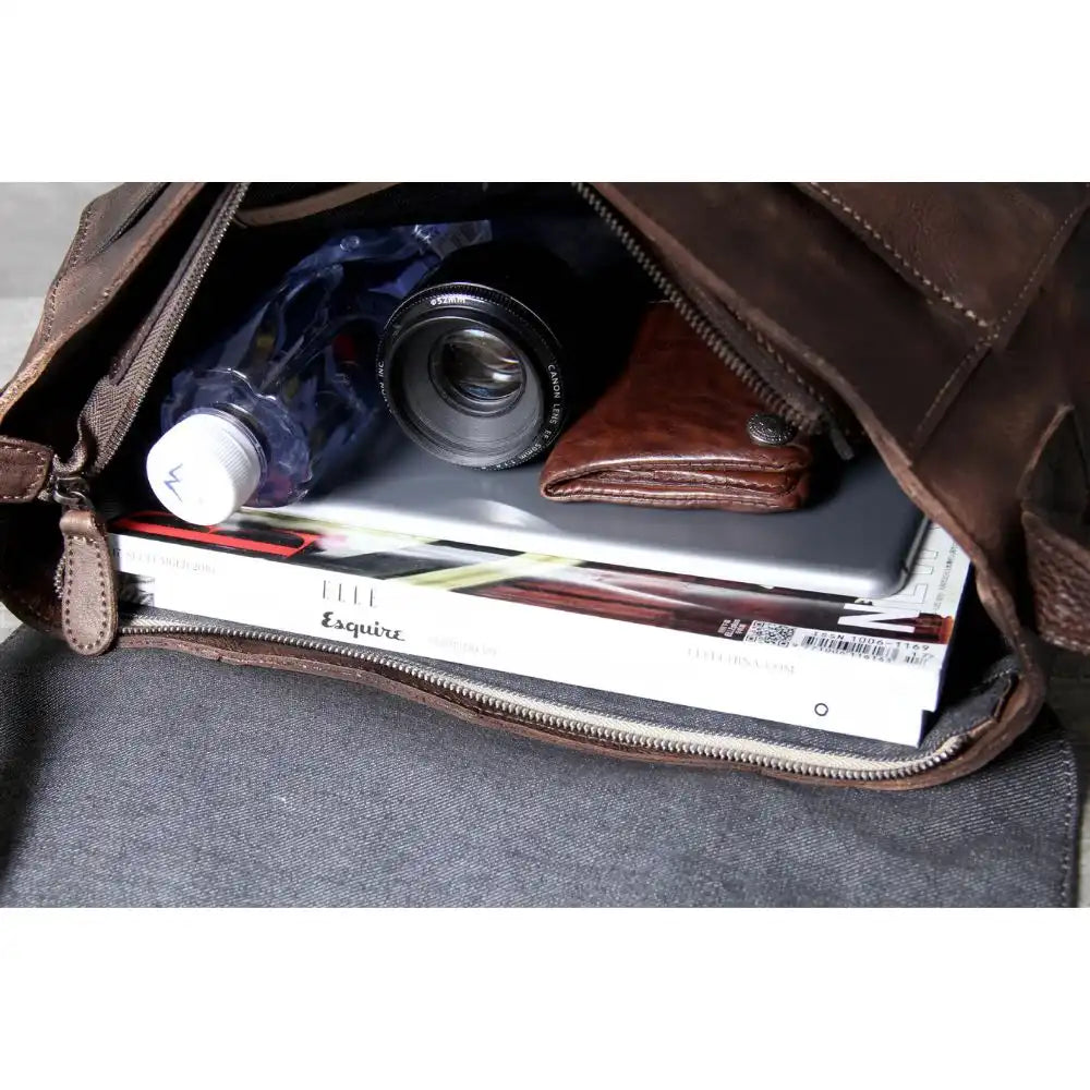 inside view of a brown bag with items such as a camera, wallets, water bottle and magazines, ideal for organizing. 