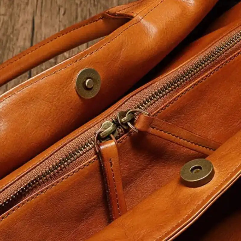 Close-up view of a brown leather bag pocket, showing the zipper and finishing details.