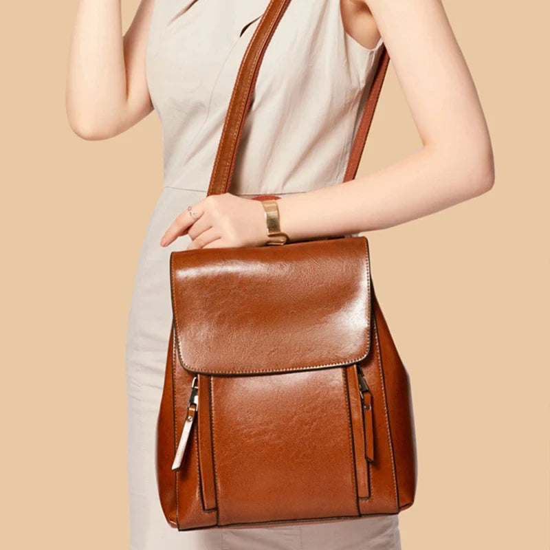 A woman holding a stylish brown leather backpack, showcasing its elegant design.
