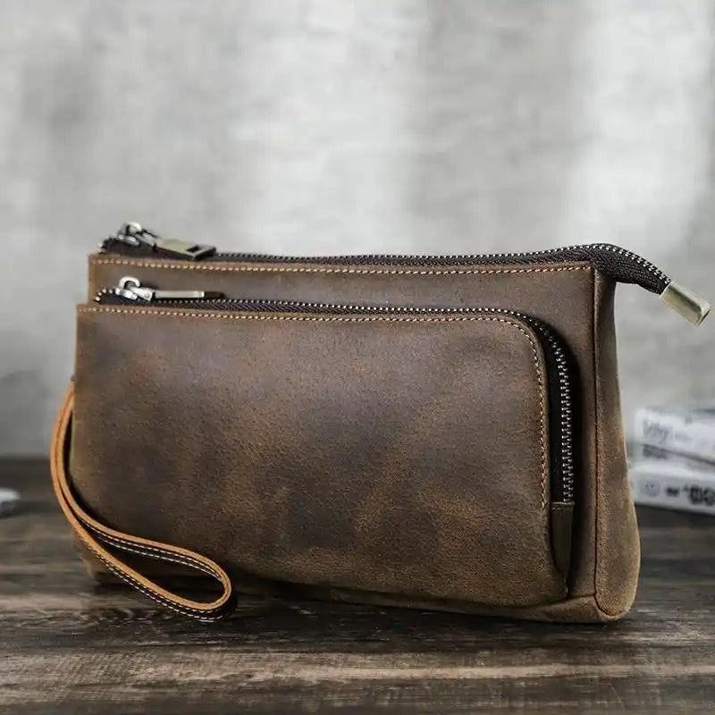 Brown leather clutch with zippers, showing an elegant and functional design, front view.