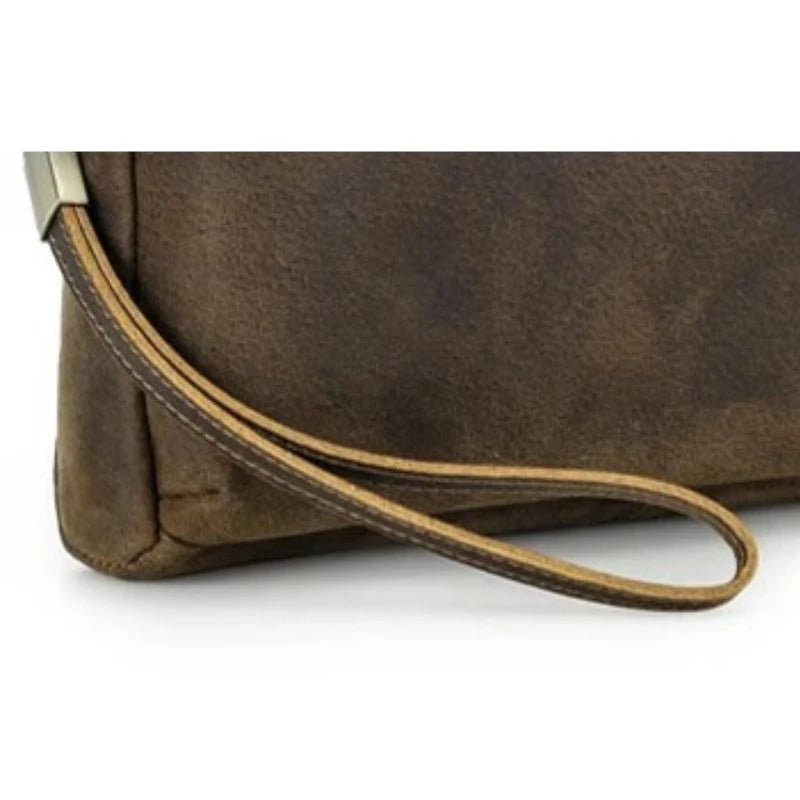 detailed view of a brown leather clutch showing the quality of its wrist strap.