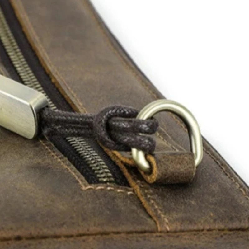 Detail of a zipper in a brown leather material, highlighting the quality of the finish and texture.