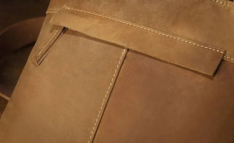 close-up of a brown leather bag that displays fine stitching, highlighting the texture and quality of the material. 