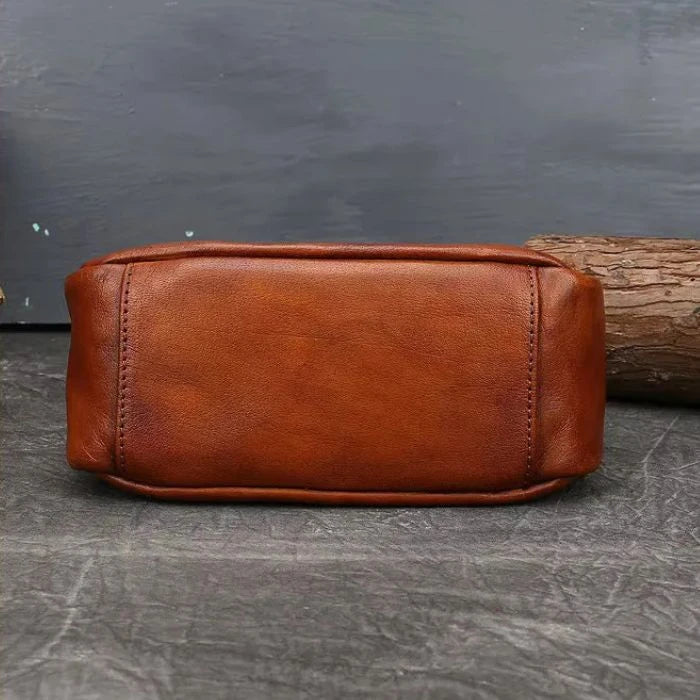 Brown leather crossbody bag with colorful feather embossed detail, bottom view.