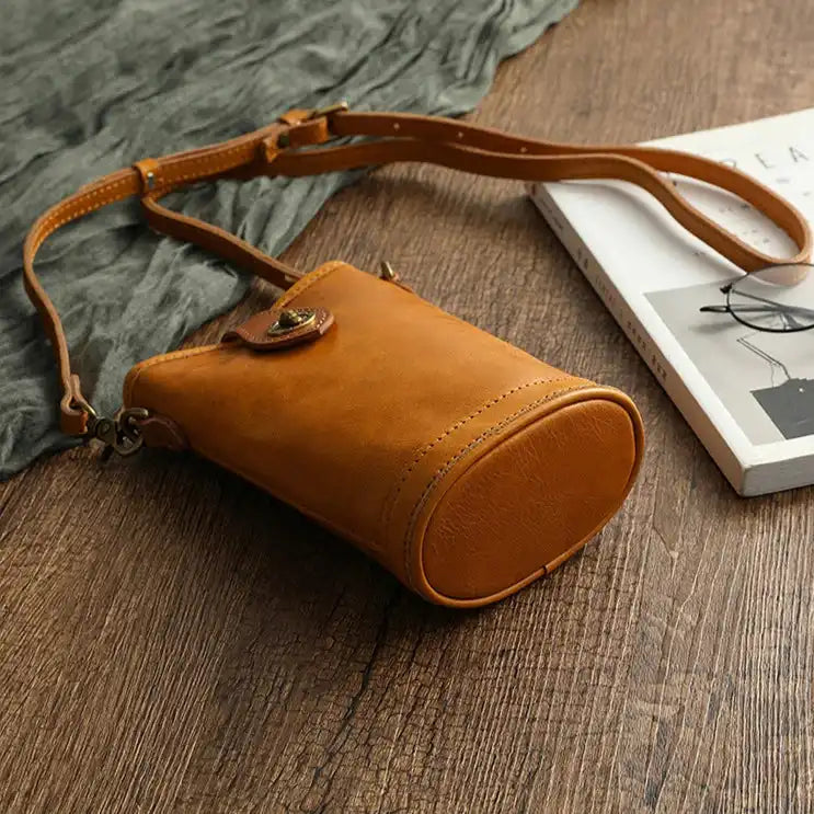 A stylish leather crossbody bag in a warm orange hue on a wooden surface.