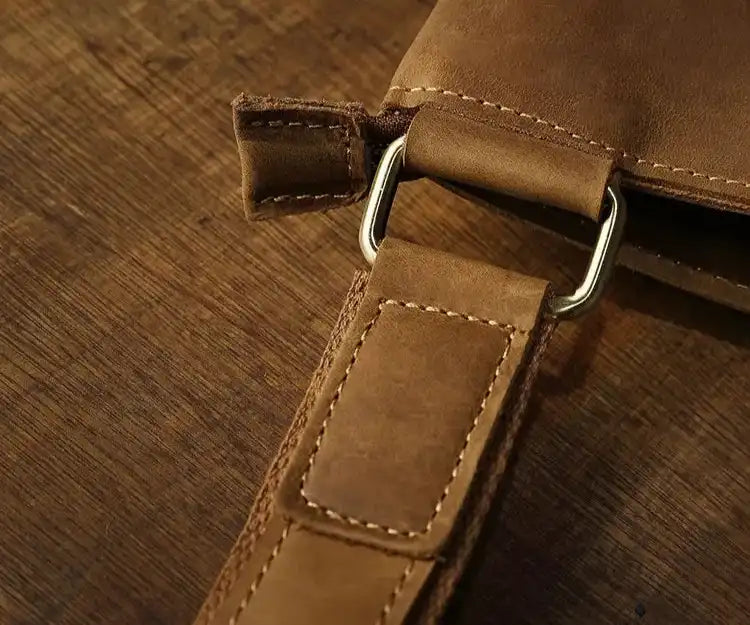 Detail of a brown leather clasp showing stitching details and metal accessories.