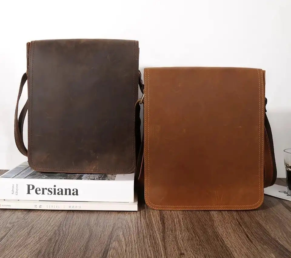 display of two leather bags in different shades of browns on top of a wooden table, front view.