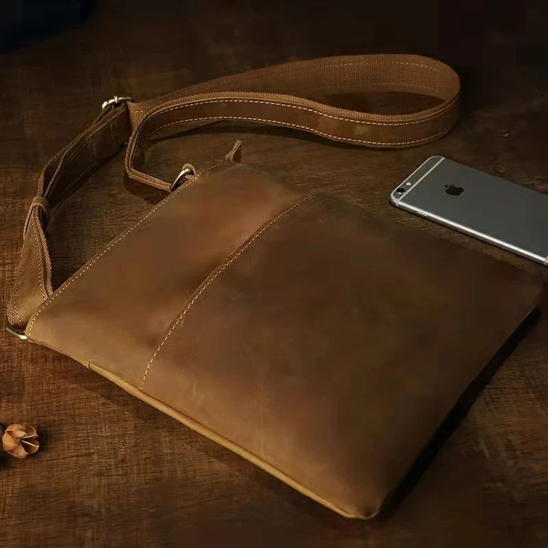 Brown leather crossbody bag, with smartphone for size reference - top view.