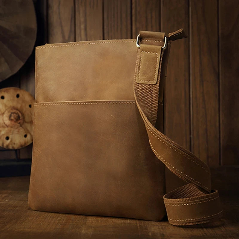 Brown leather crossbody bag, with adjustable strap, stylish design and front pocket for essentials. 