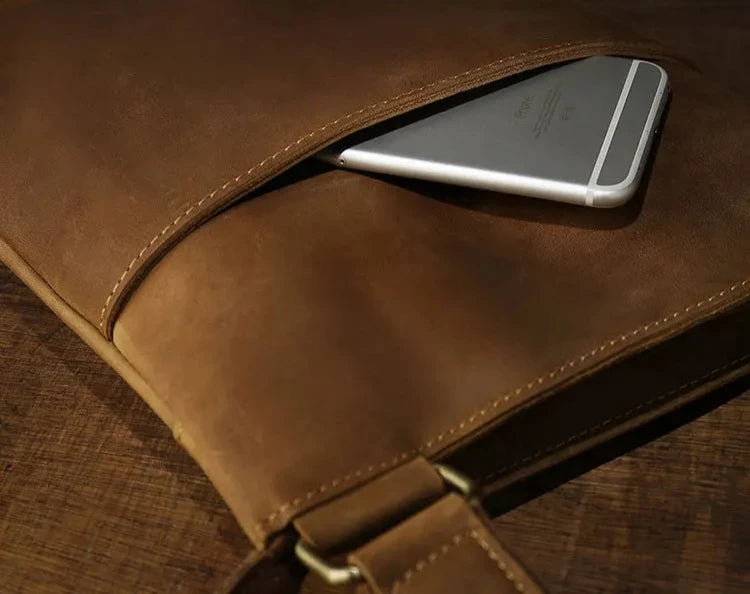 brown leather bag showing a smartphone partially visible inside the pocket.