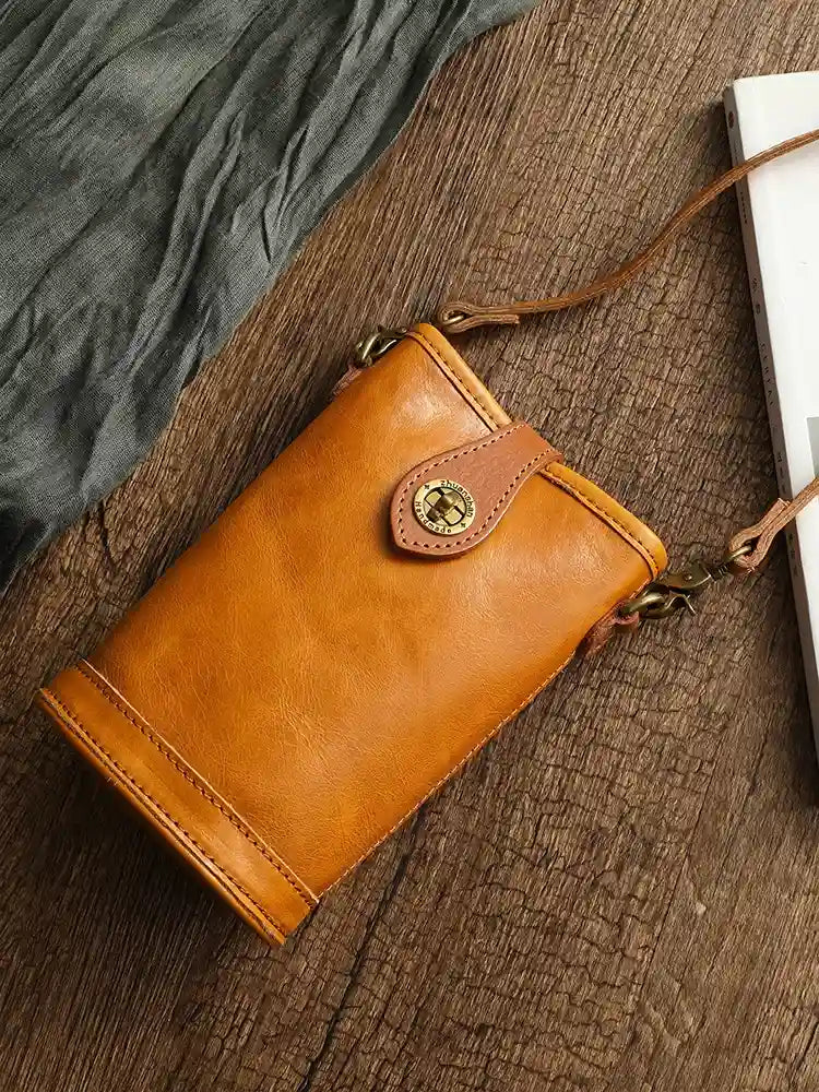 Chic green leather crossbody bag with gold accents on a rustic background, top view.