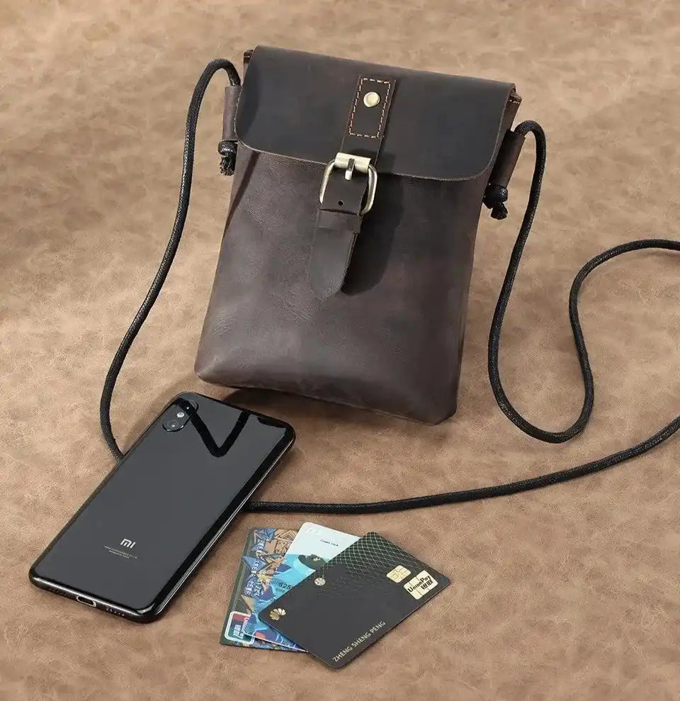 Stylish brown leather crossbody bag with smartphone and credit cards.