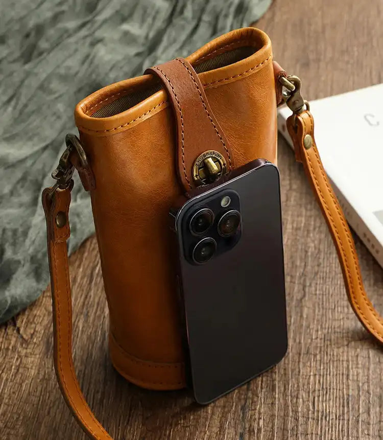 Stylish leather phone bag featuring a smartphone resting against it for size reference.