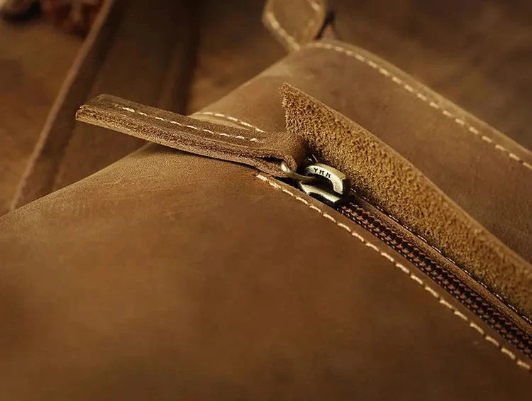 Detailed image of a zipper in a brown leather bag, highlighting the texture and high quality finish of the product.