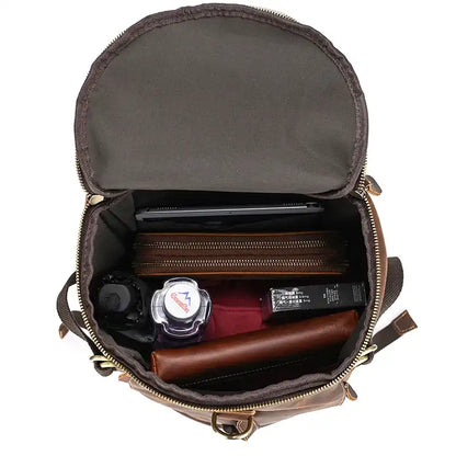 Inside view of a brown leather duffle bag, showing its organized contents, including a tablet, wallet and other useful items.