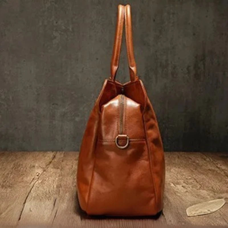 Brown leather handbag with an elegant and modern design, stylish soft handles and detachable strap, side view.