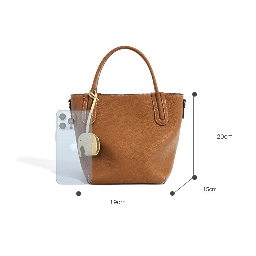 tylish brown leather handbag with dimensions, next to a smartphone for size reference.