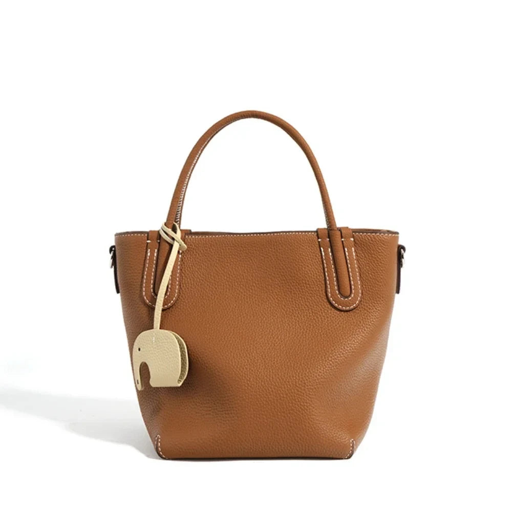 A stylish brown leather handbag with a unique elephant charm - front view.