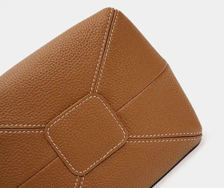 bottom view of an elegant brown leather bag with textured finish and detailed stitching.