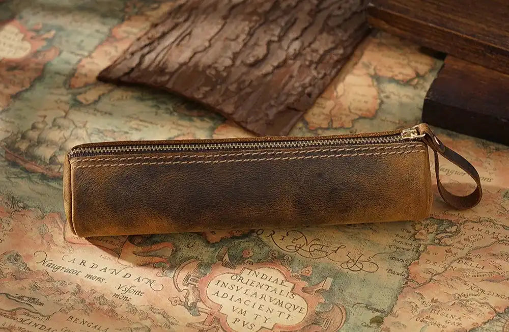 Elegant brown leather pen case on an antique map, side view.