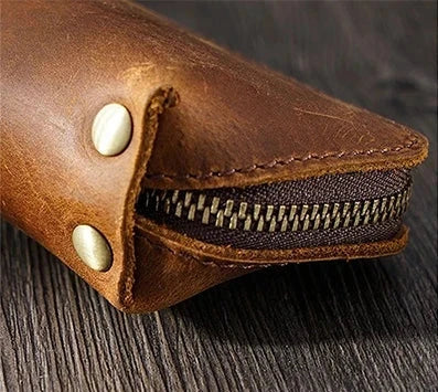 Close-up of a brown leather zippered case with brass buttons.