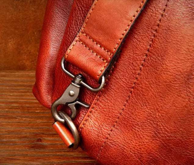 Close-up of a brown leather bag clasp and strap detail.