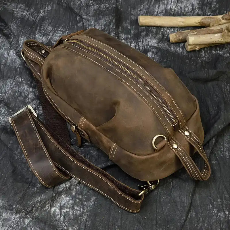 A vintage leather shoulder bag with a zipper, double handles and adjustable strap, top view.