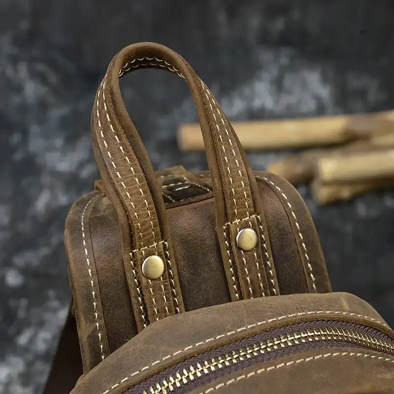 Close-up view of a brown leather bag handle with light stitching details.