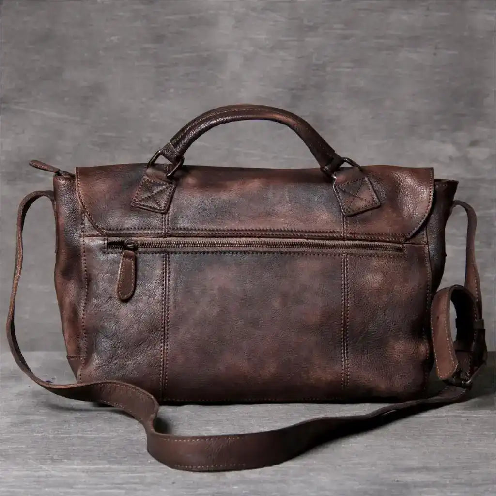 Brown leather bag with shoulder strap, soft handle and back zipped pocket, back view.