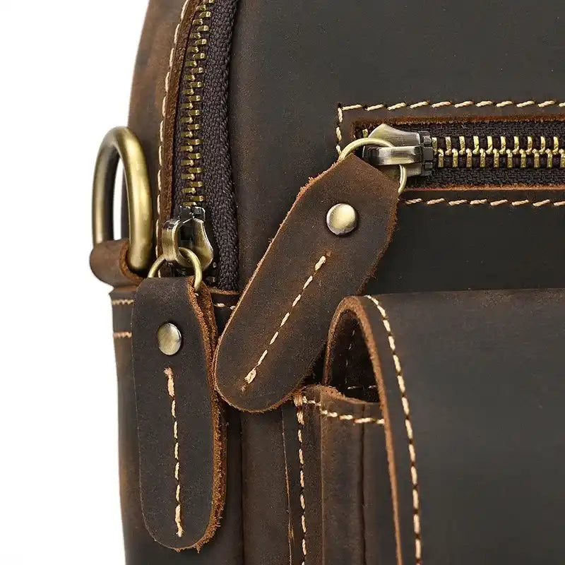 Detail of a brown leather bag, showing zipper, stitching and metal accessories.