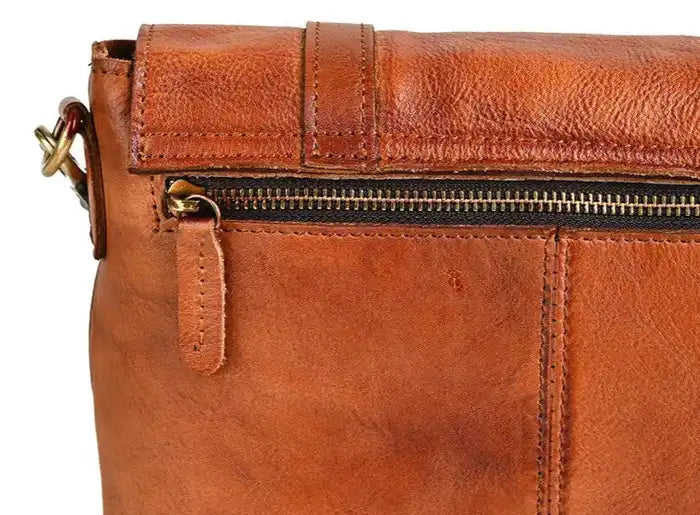 Detail view of a brown leather bag showcasing its texture and zipper.