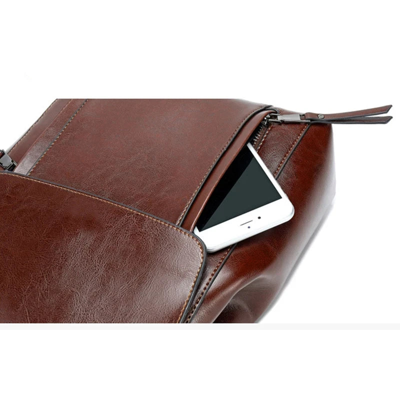 Close-up of a brown leather bag with a smartphone inside a zippered pocket.