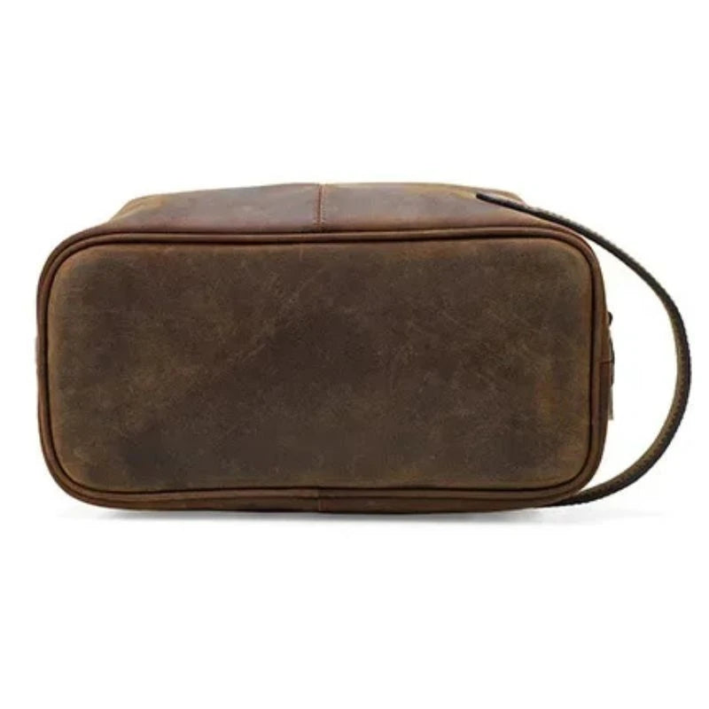 Brown leather toiletry bag with zipper closure and soft handle, bottom view.