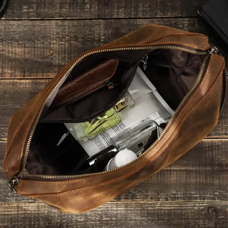 interior of a brown leather toiletry bag with zipper closure showing interior pockets and some personal items.