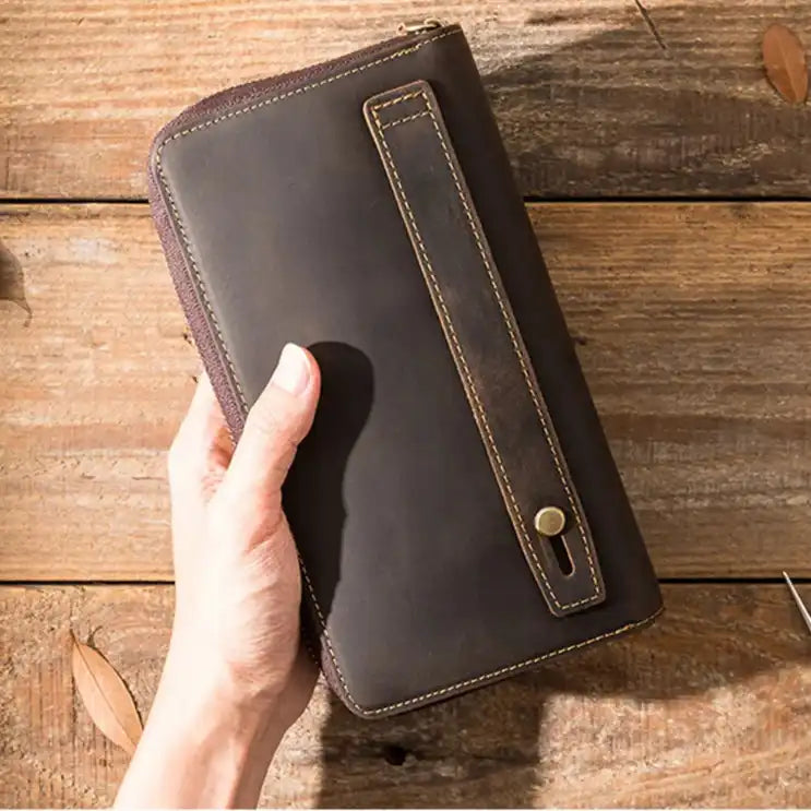 a hand holding an elegant brown leather wallet on a wooden surface, highlighting its functional design.