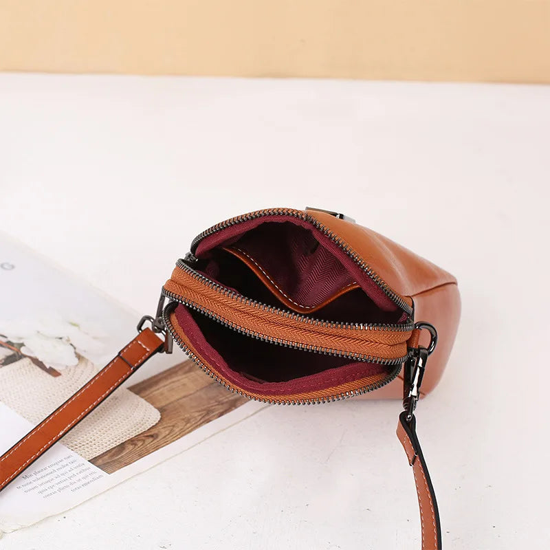 Compact caramel crossbody bag showcasing its elegant interior compartments and zippers.
