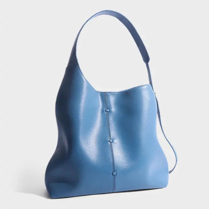 Elegant blue leather bag with a modern design and adjustable strap, front view.