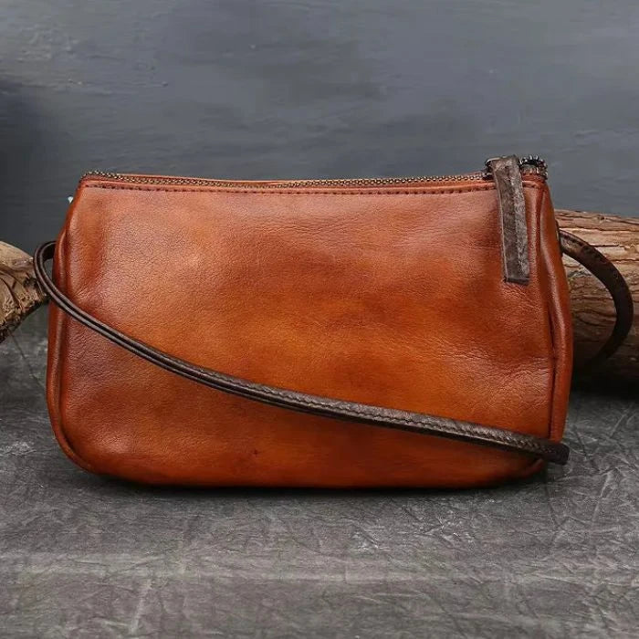 Brown leather crossbody bag with colorful feather embossed detail, back view.
