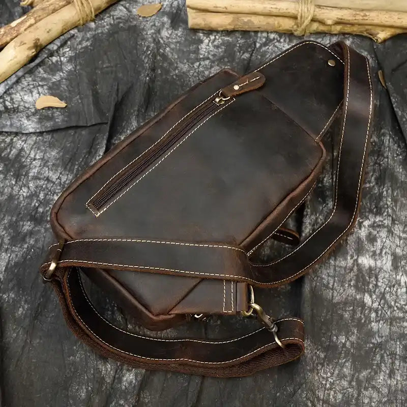 Coffee brown leather bag with a classic design and a long handle and back zipped pocket, top view.