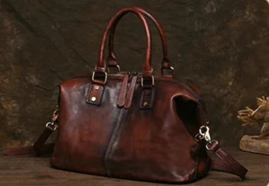 Vintage style coffee brown leather bag with handles and long strap, front view. 