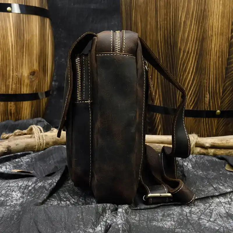 a coffee brown leather bag with a modern design, highlighting zipper and adjustable strap details, side view.