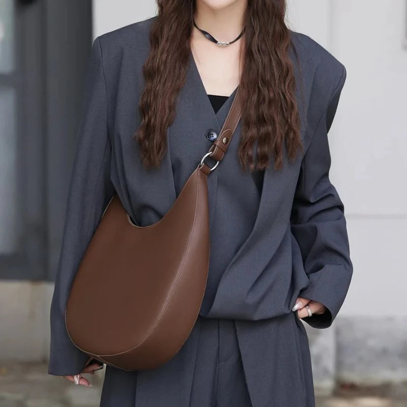 model wearing a coffe brown leather bag across her body.