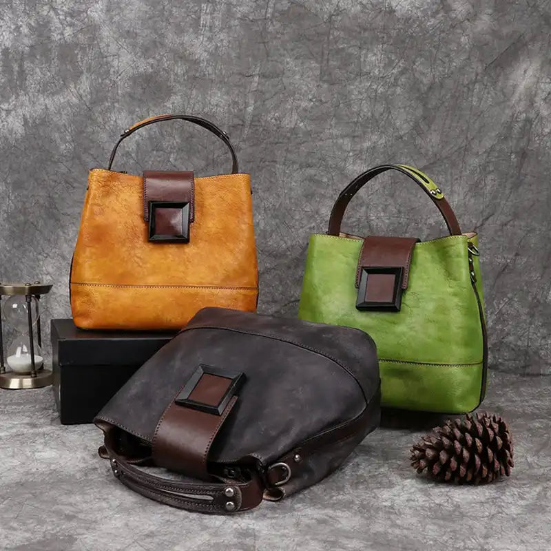 Set of elegant women's leather bags in vibrant colors: orange, green and gray, front view.