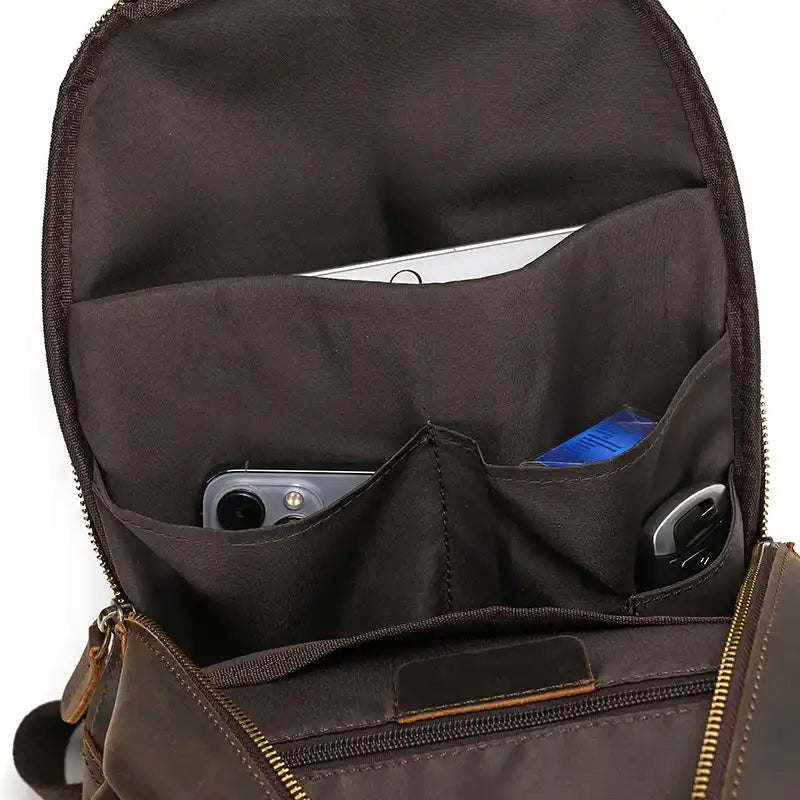 Interior of a leather bag with several compartments for organization, containing a cell phone and other items. 